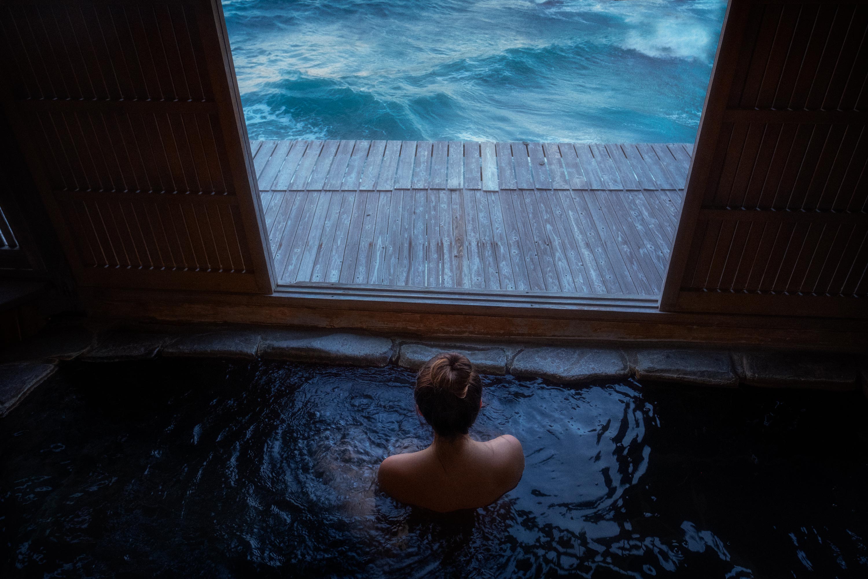 Japanerin im Onsen-Bad mit Meerblick am Wasser