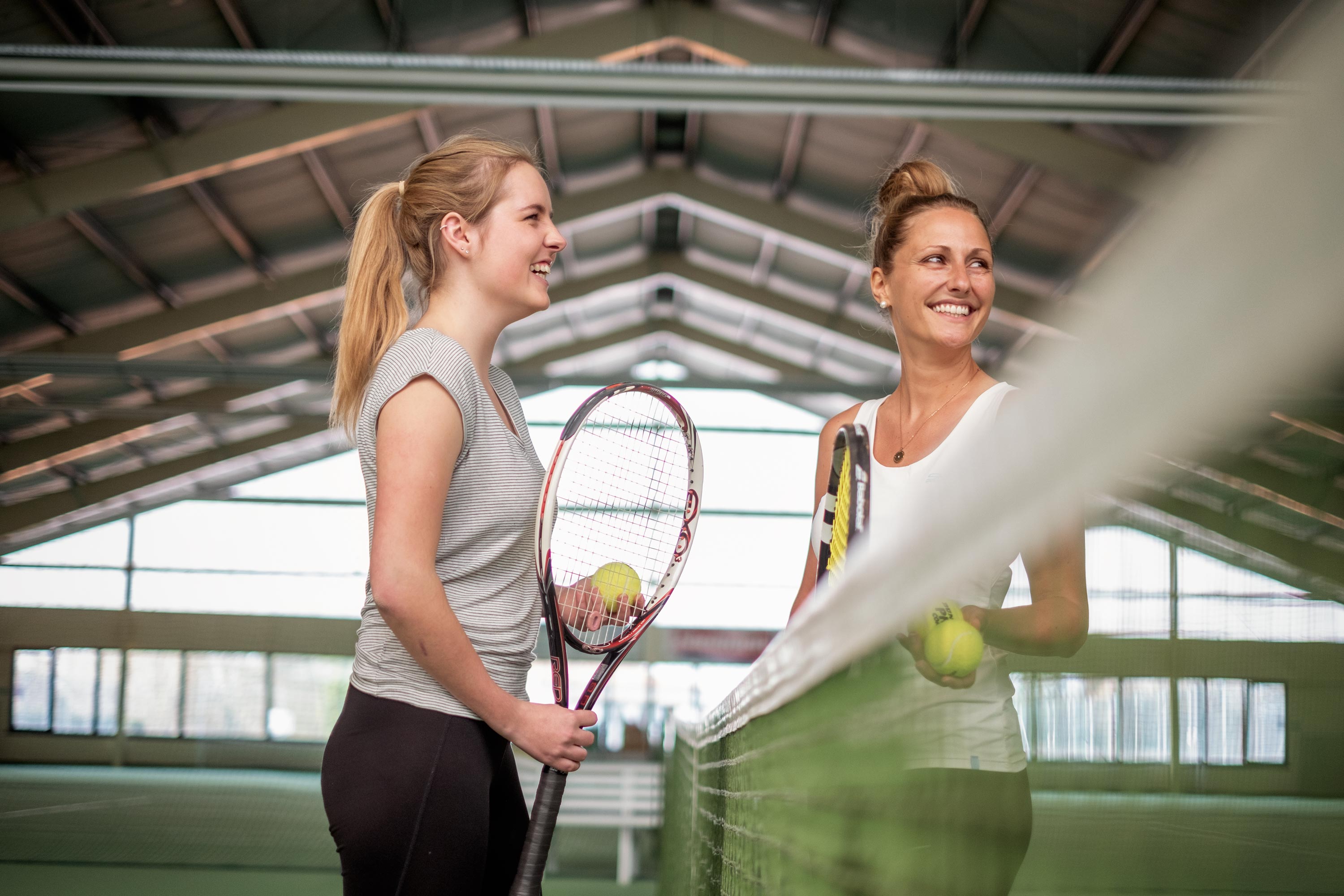 Work Life Balance Thema in der Recruiting Kampagne zwei Mitarbeiterin beim Tennis freudig am Netz mit Tennisschlägern in der Hand