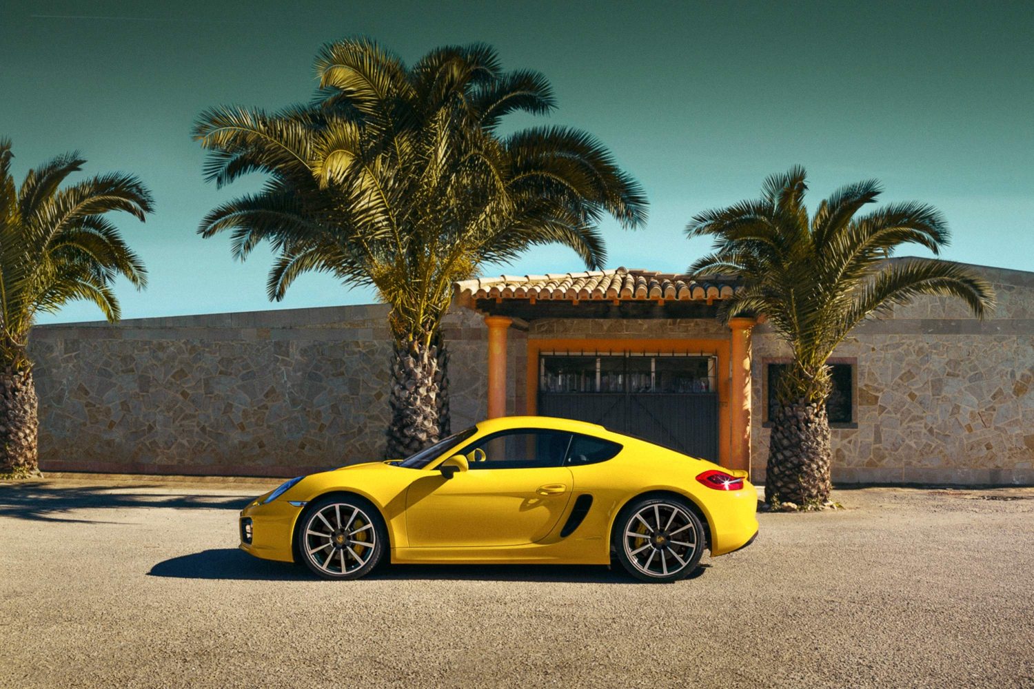 Gelber Porsche vor einem Haus mit Palmen