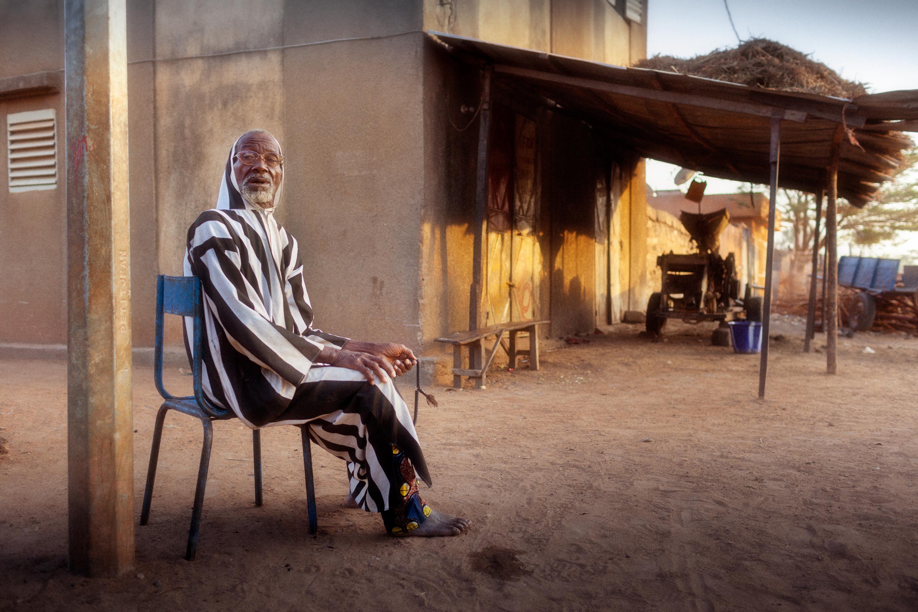 alter Mann sitzt auf einem Stuhl in der Abendsonne in Mali