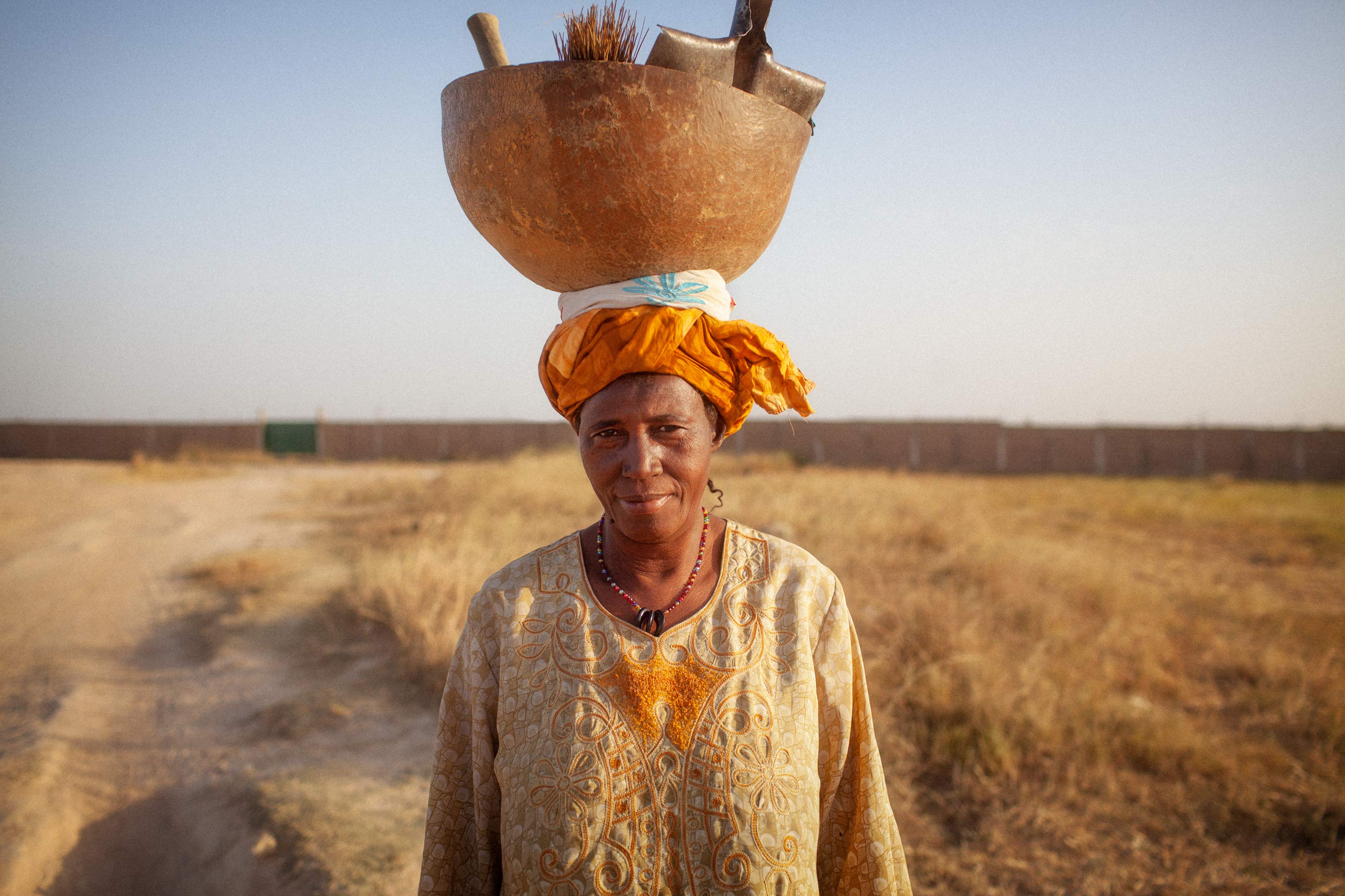 Frau trägt ihr Putzzeug in Mali auf dem Kopf