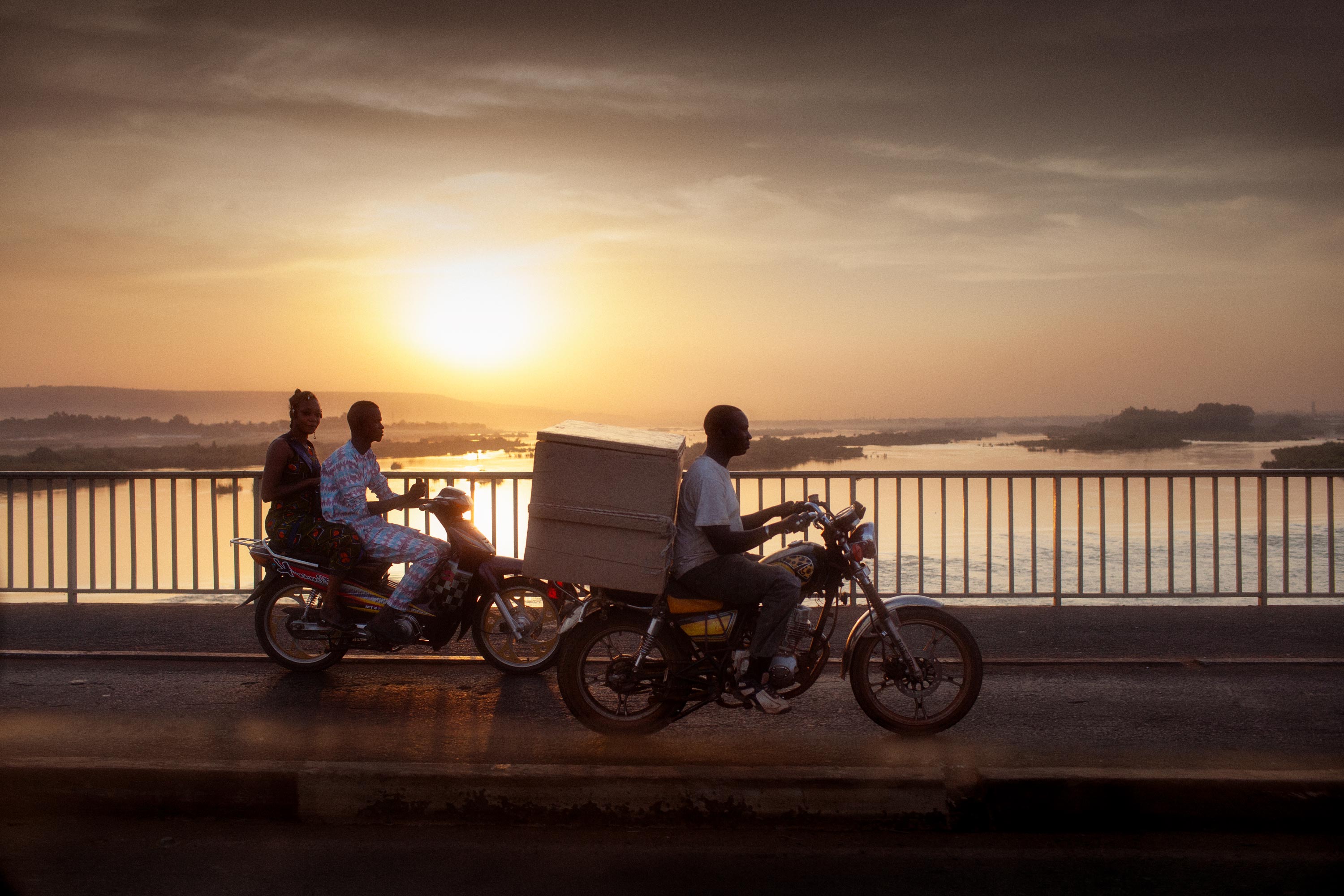 Abendstimmung auf einer Flussbrücke in Mali Afrika - Motorradfahrer bei Sonnenuntergang