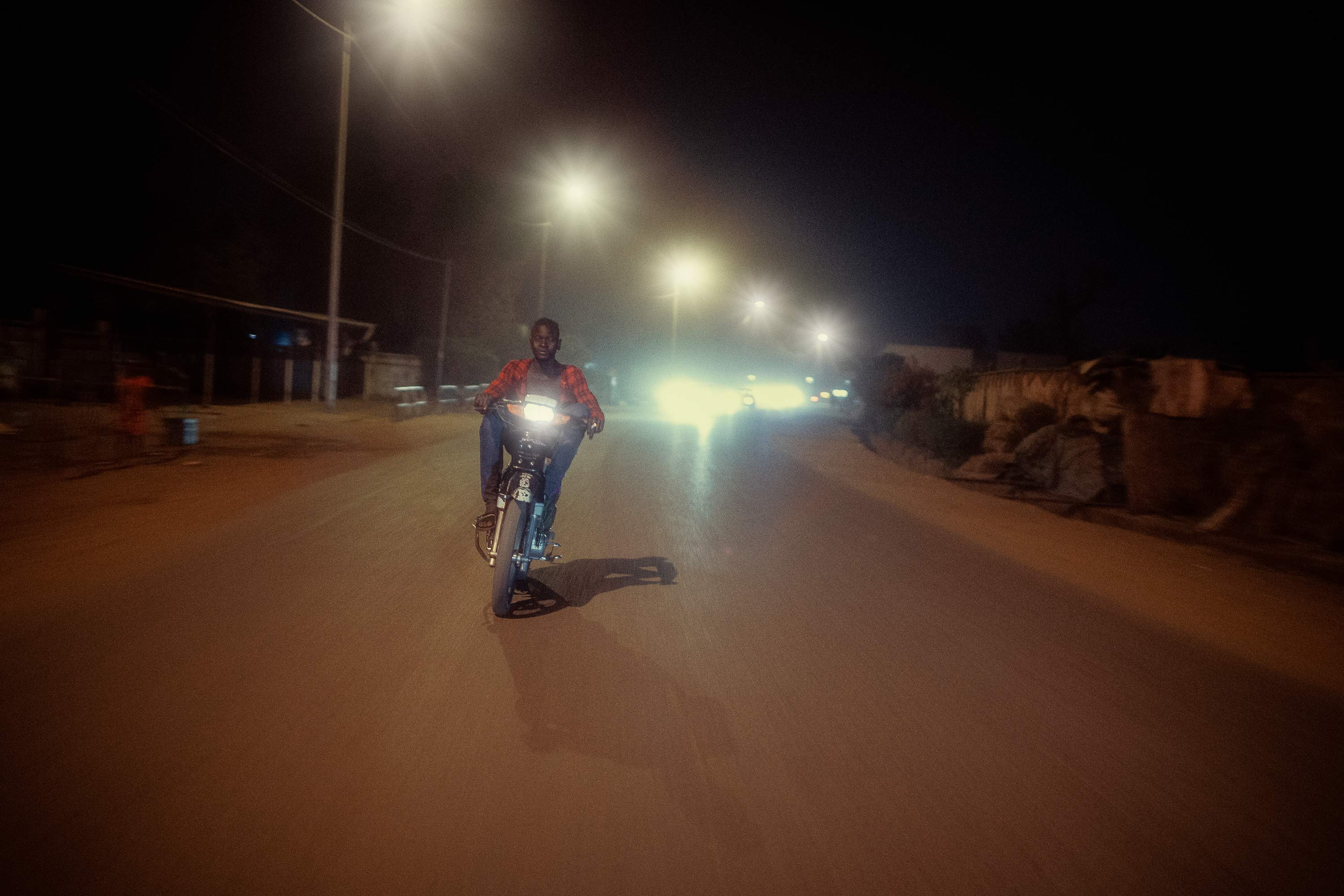 junger Mann bei Nacht auf einer Straße in Mali