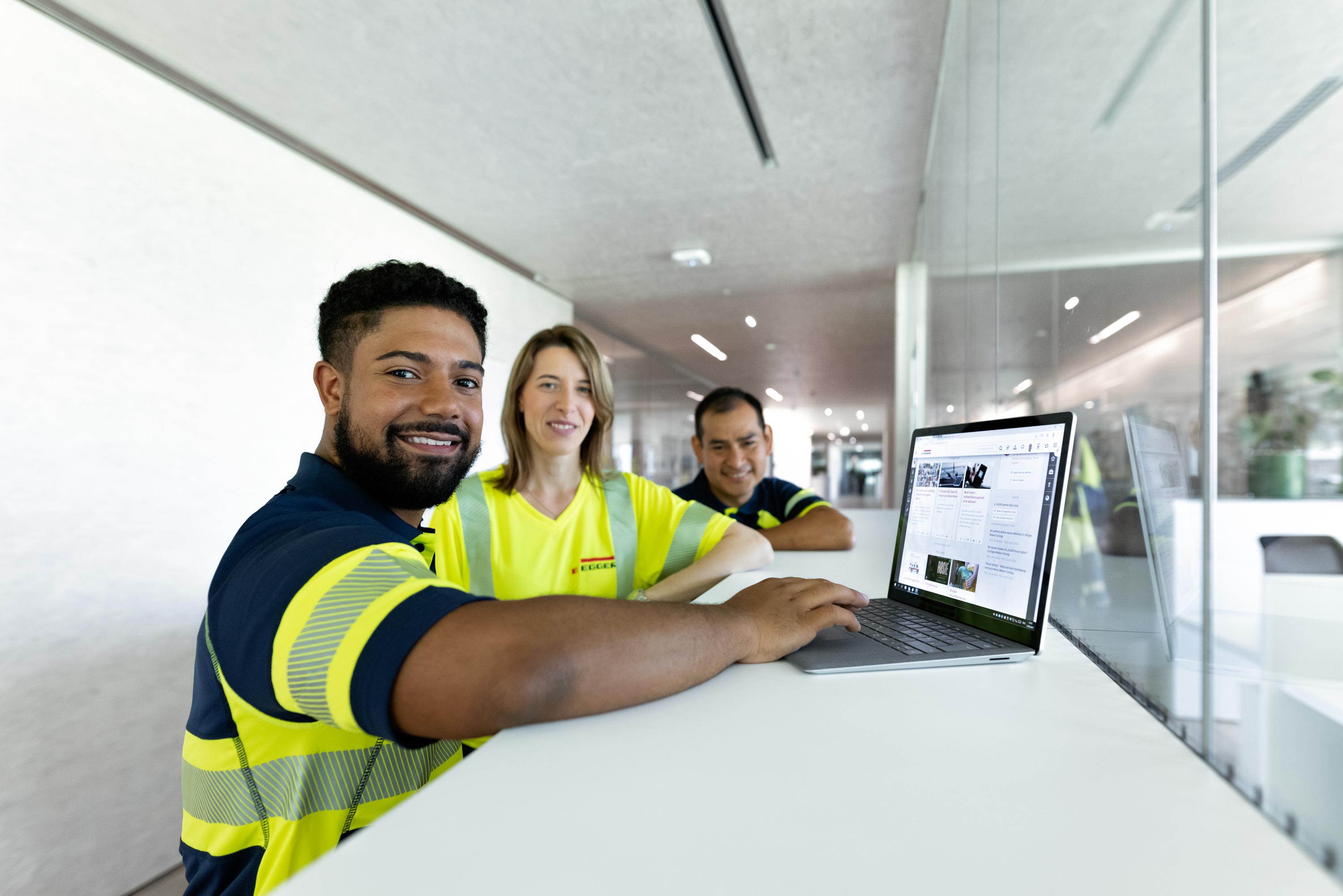 Corporate Fotografie, drei Mitarbeiter stehen freudig vor einem Laptop