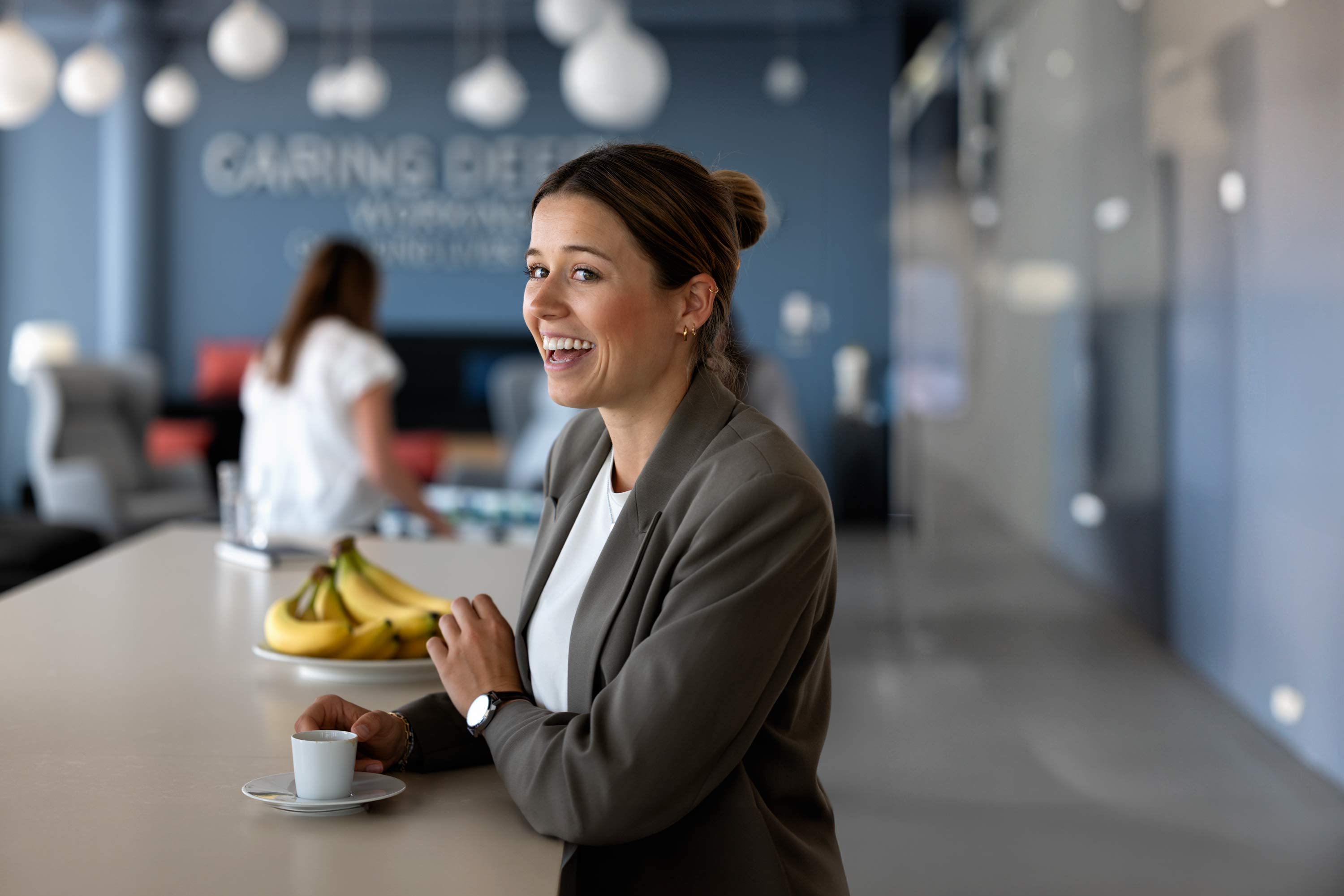 Employer Branding Foto, junge Geschäftsfrau schaut freudig in einem lichtdurchfluteten Office in der Kreativbranche